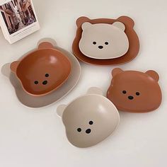 four brown and white plates with bear faces on them, sitting next to each other