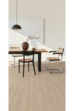 a dining room table with chairs and a vase on top of it, in front of a white wall