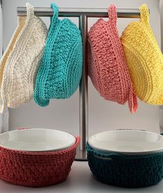 four knitted dishes are hanging on a rack with three bowls in front of them