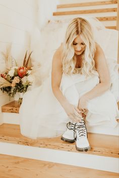 a woman in a white dress is tying her shoes