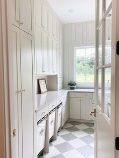 a white kitchen with checkered flooring and lots of cupboards on the wall