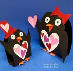 two paper penguins with hearts on their heads, one is black and the other is pink