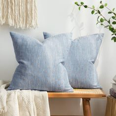 two blue pillows sitting on top of a wooden bench next to a potted plant