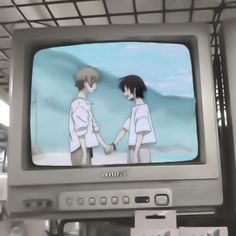 two people standing in front of a tv with an anime character on it's screen