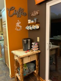 a small table with coffee cups on it in front of a wall that says coffee