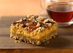 a piece of cake sitting on top of a wooden table next to a cup of tea