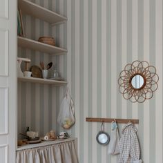 a kitchen with striped walls and white cupboards, hanging utensils on the wall