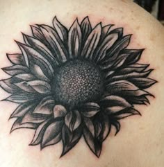 a sunflower tattoo on the back of a woman's shoulder