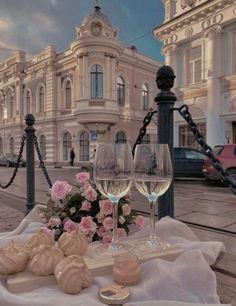 two wine glasses sitting on top of a table next to some bread and pastries