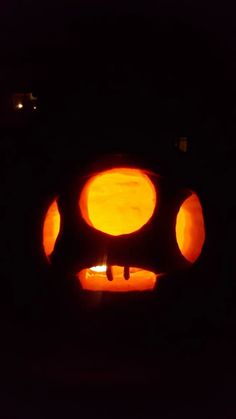 a close up of a lit candle in the shape of a face on a black background