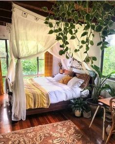 a bedroom with a canopy bed and plants hanging from the ceiling