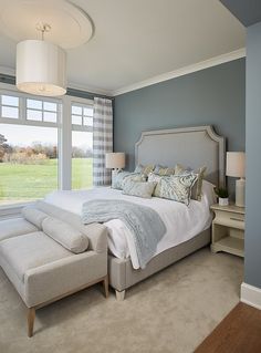 a bedroom with a large bed sitting next to a window filled with lots of windows