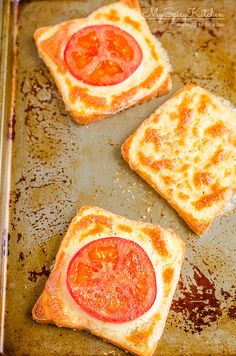 three slices of toast with tomatoes on them sitting on a baking sheet in the oven