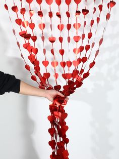 a person holding up a bunch of red hearts