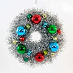 a christmas ornament hanging on a white wall with silver tinsel and colorful ornaments