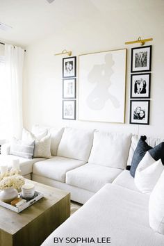 a living room with white couches and pictures on the wall