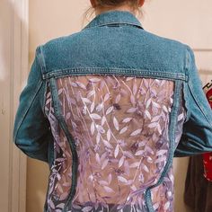 the back of a woman's jean jacket with leaves on it