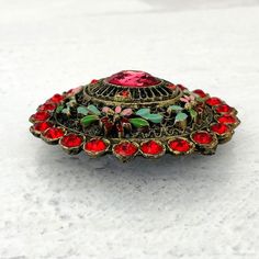 Authentic Vintage Little Nemo Oval Floral Brooch Pin Red Rhinestones Enamel SignedOutstanding colors and in excellent condition with minor enamel loss in tiny areas. All stones are present and original. Marked L/N on the reverse. A gorgeous rare brooch! This beautiful brooch measures 2 3/16 of an inch (55mm) by 1 15/16 of an inch (50mm). It is approximately 1/2 deep (13mm) deep at the center not including the pin stem.. Please see the photos for details and email us any questions.  Thank you for your interest! Gold Lion, Floral Brooch, Jewelry Pins, Stick Pins, Red Rhinestone, Metropolitan Museum Of Art, Brooch Pin, Silver Tone, Stone