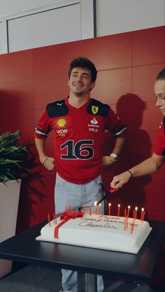 a man standing in front of a cake with candles on it