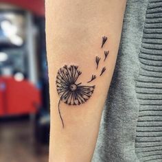 a small dandelion tattoo on the arm