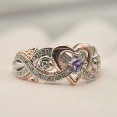 a close up of a ring on a white surface with a purple stone in the middle