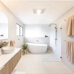 a bathroom with two sinks and a bathtub in the middle, along with towels hanging on the wall