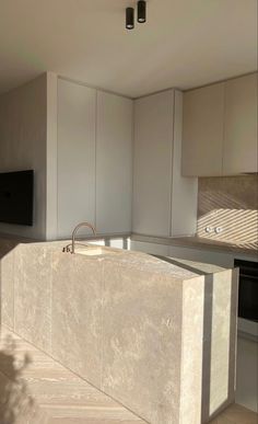 an empty kitchen with white cabinets and marble counter tops in front of a flat screen tv