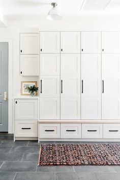 a room with white cupboards and rug on the floor in front of it's doors