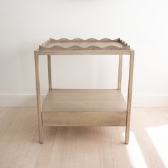 a wooden table sitting on top of a hard wood floor next to a white wall