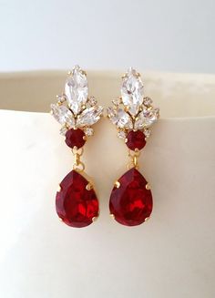 two pairs of red and white earrings with crystal stones on top of each earring