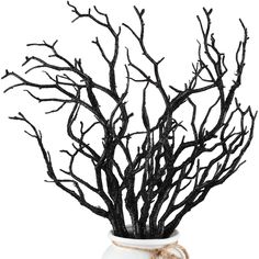 a white vase filled with black branches on top of a wooden table next to a rope