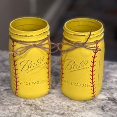 two yellow mason jars with baseball stitching on them