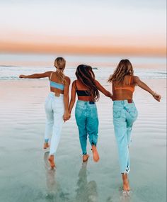 three women walking on the beach holding hands