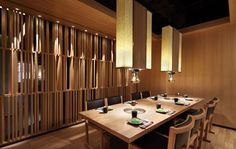 a long table with place settings in front of wooden partitions and lights on the wall