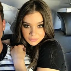 a man and woman are sitting in the back seat of a car, posing for a photo