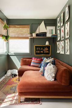 a living room with green walls and pictures on the wall above the couch, along with a dog laying on the floor