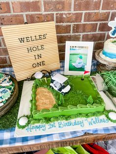 a green birthday cake sitting on top of a table next to a sign that says, we're hole in one