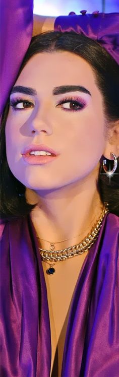 a close up of a person wearing jewelry and a purple dress with large hoop earrings