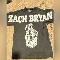 a black t - shirt with the words zach bryan on it sitting on a carpet