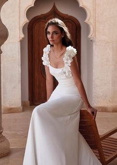 a woman in a white dress sitting on a bench