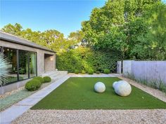 two large white balls sitting on top of a grass covered field in front of a house