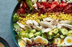 a large salad with hard boiled eggs, corn, tomatoes and avocado in it