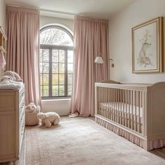 a baby's room with pink curtains, crib and stuffed animals on the floor