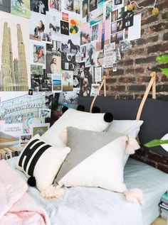 a bed topped with lots of pillows next to a wall covered in pictures and photos