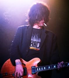 a man with long hair playing an electric guitar