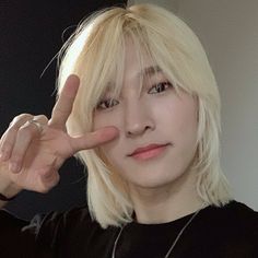 a young man with blonde hair making the vulcan hand sign while wearing a black t - shirt