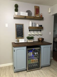 a small refrigerator in the corner of a room with shelves on the wall above it