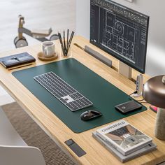 a desk with a keyboard, mouse and book on it in front of a computer monitor