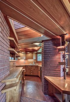 an open kitchen with wooden cabinets and counter tops, along with a brick wall in the background