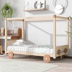 a child's bed with wooden wheels in a white room, next to a potted plant